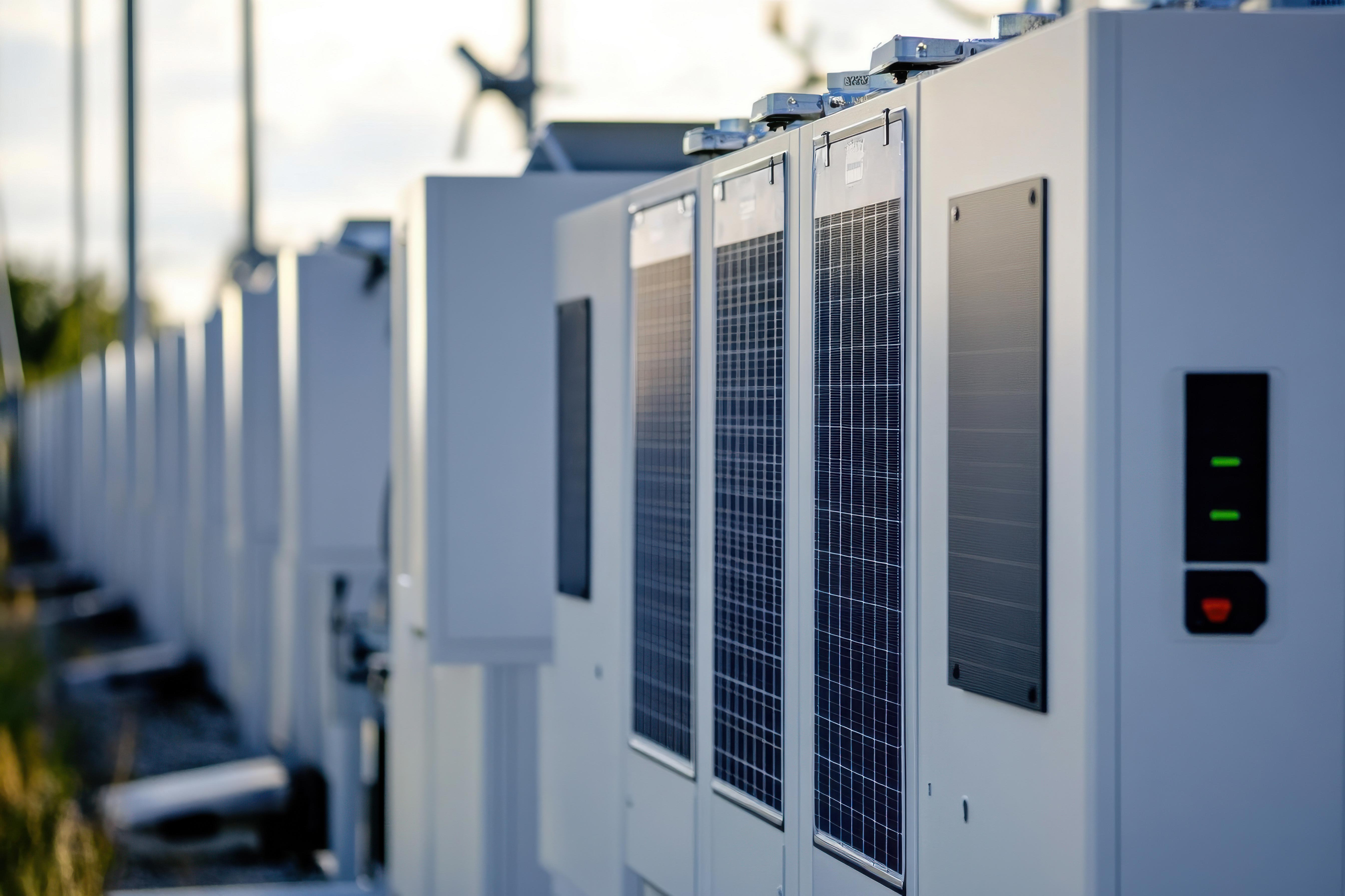 Reihe von weißen Batteriespeichern im Freien bei Sonnenuntergang; moderne Energieinfrastruktur.